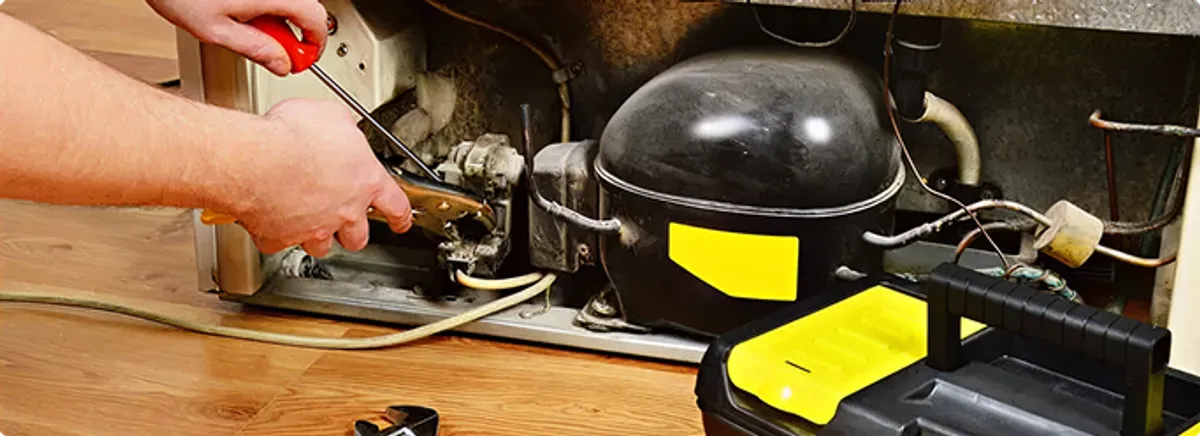 Refrigerator repair technician fixing the compressor and wiring in Placentia, CA