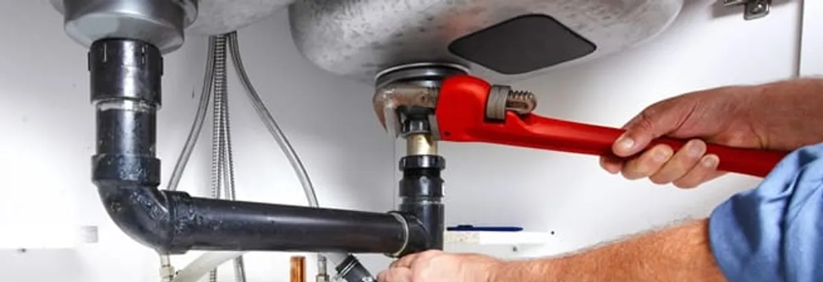 Garbage disposal repair technician tightening the sink drain and disposal connection in Orange, CA