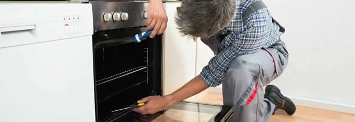 Oven repair technician inspecting and servicing an electric oven in Orange, CA