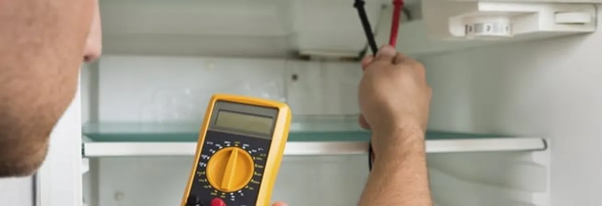 Refrigerator repair technician testing electrical components with a multimeter in Orange, CA